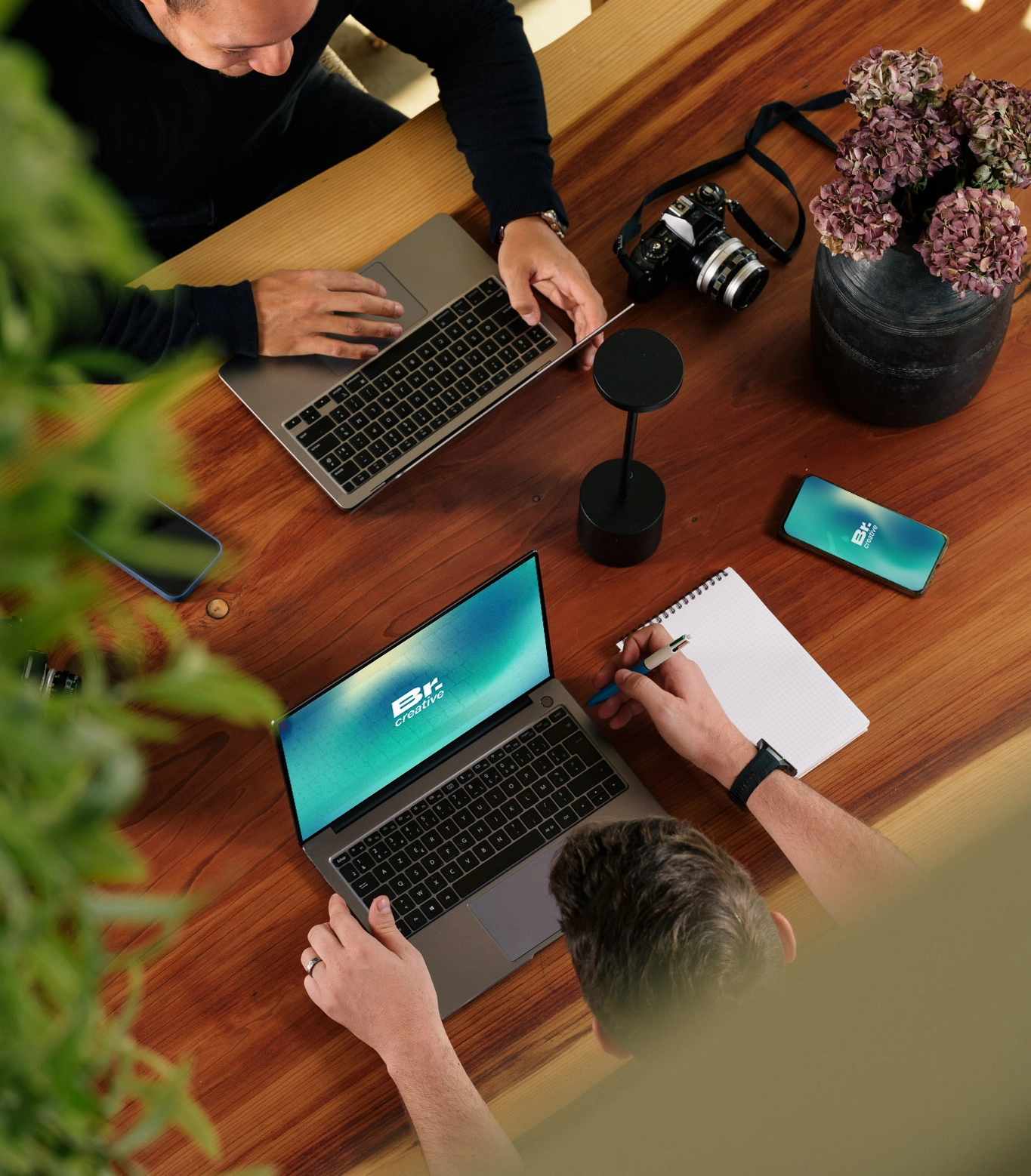 Vue en plongée d’un espace de travail collaboratif avec table en bois et outils créatifs – Br.creative