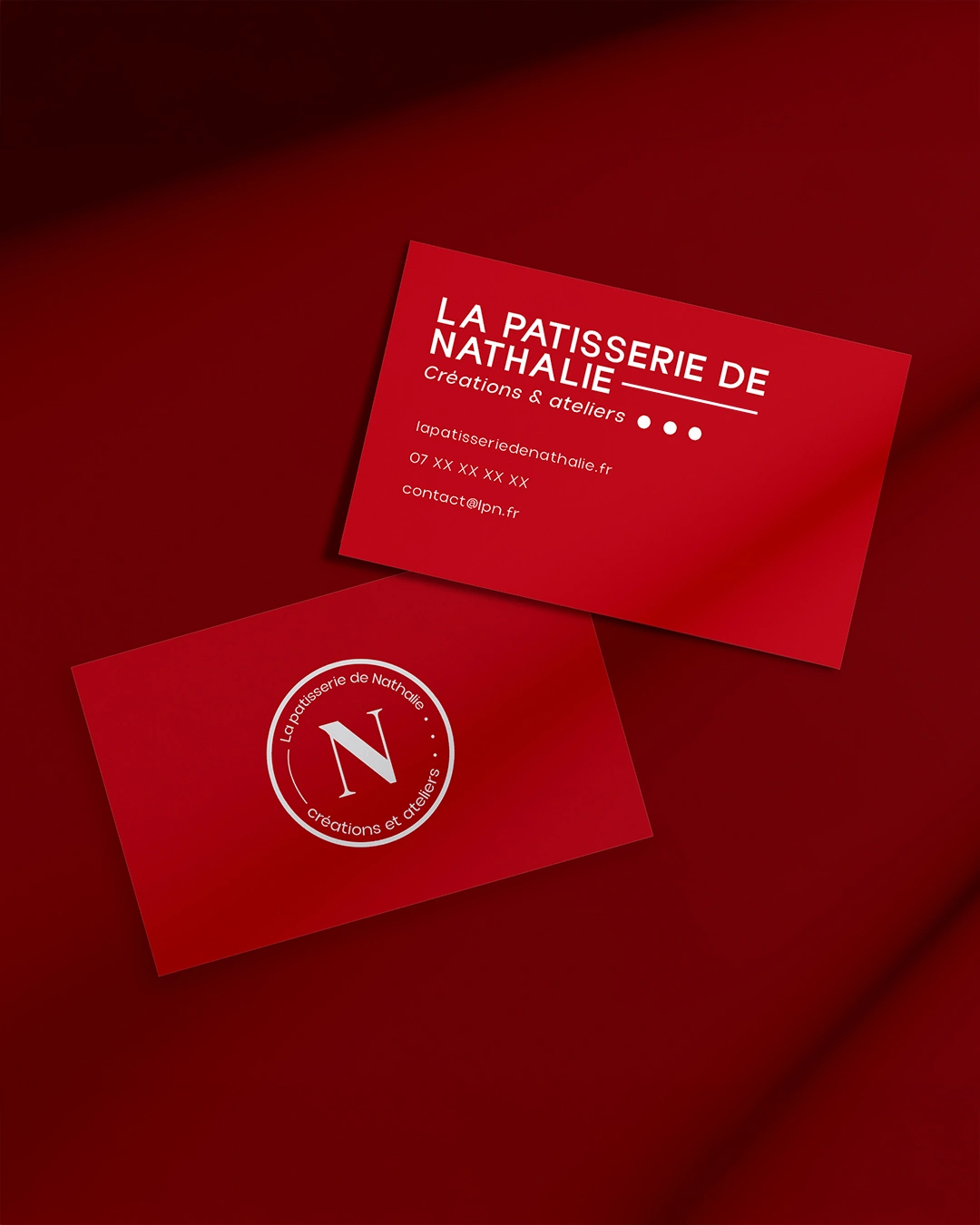 Cartes de visite rouges posées sur fond assorti, logo et nom de La Pâtisserie de Nathalie
