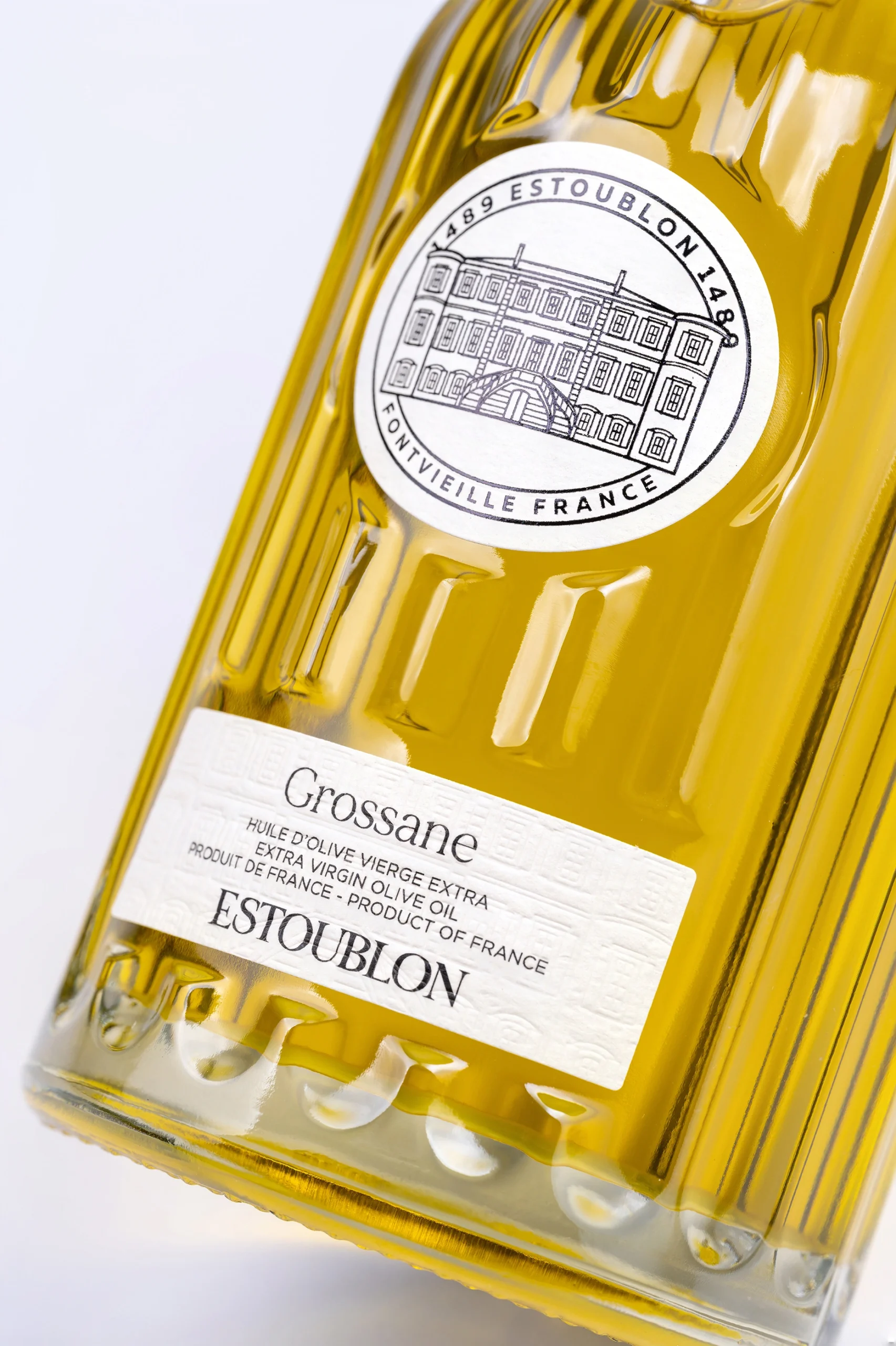 Bouteille d’huile d’olive Grossane du Château d’Estoublon inclinée sur fond blanc