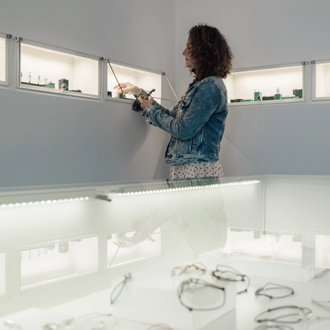 Claire réorganise les bijoux dans la vitrine intérieure de la boutique Adrien Moniquet à Maussane