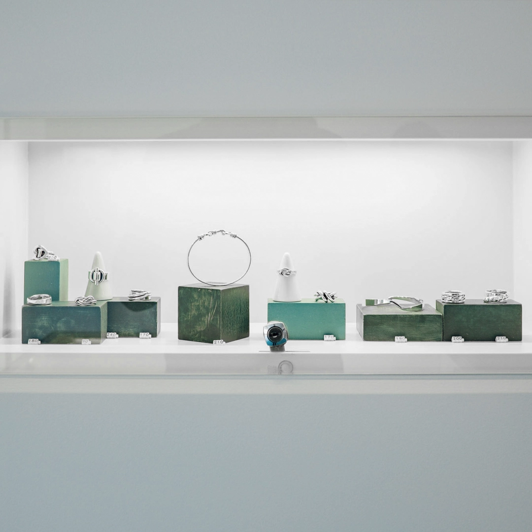 Présentation de bijoux dans une vitrine blanche minimaliste de la boutique Adrien Moniquet à Maussane