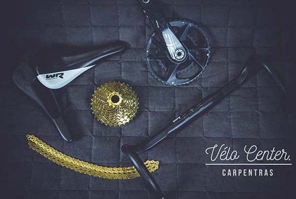 Vue en plongée sur des pièces détachées de vélo route chez Vélo Center Carpentras, incluant cassette, pédalier et chaîne