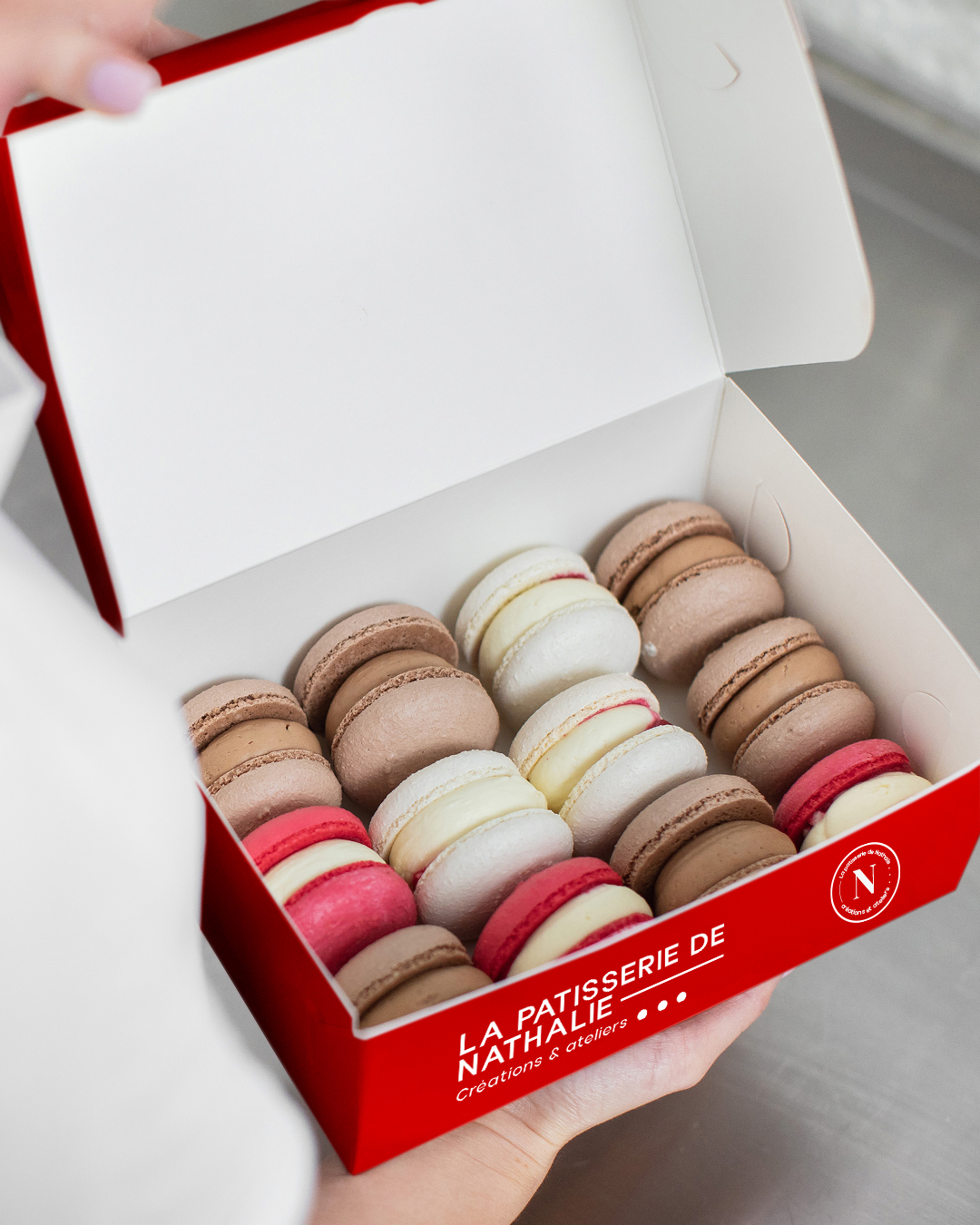 Coffret ouvert de macarons variés posés sur une table, création de La Pâtisserie de Nathalie