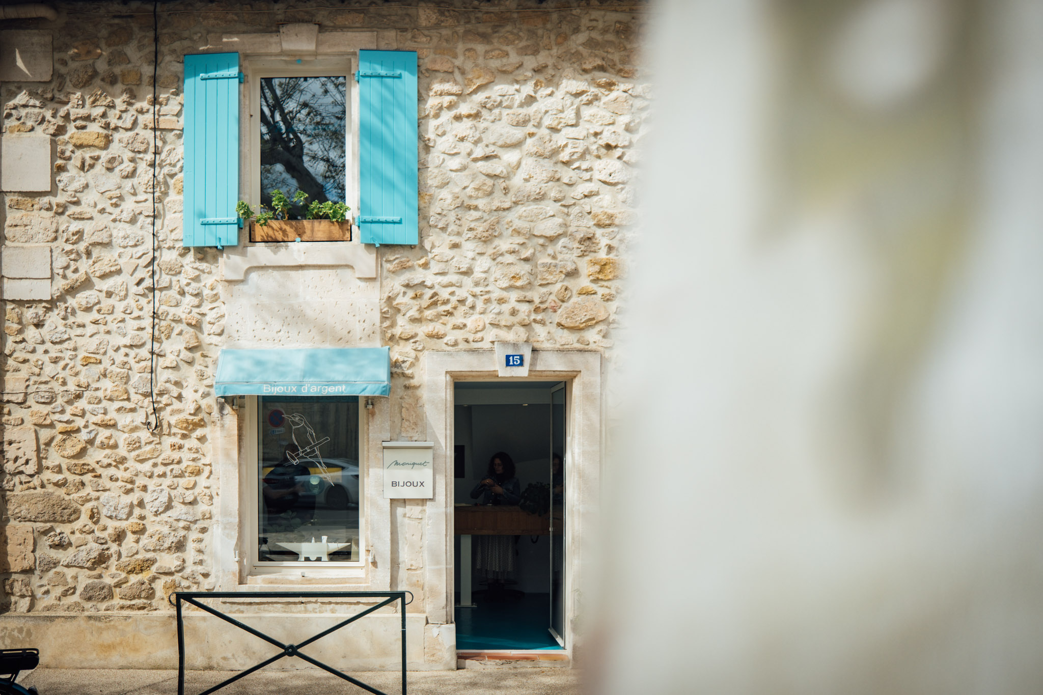 Vue d’ensemble de la façade en pierre de la boutique Adrien Moniquet à Maussane-les-Alpilles avec porte ouverte
