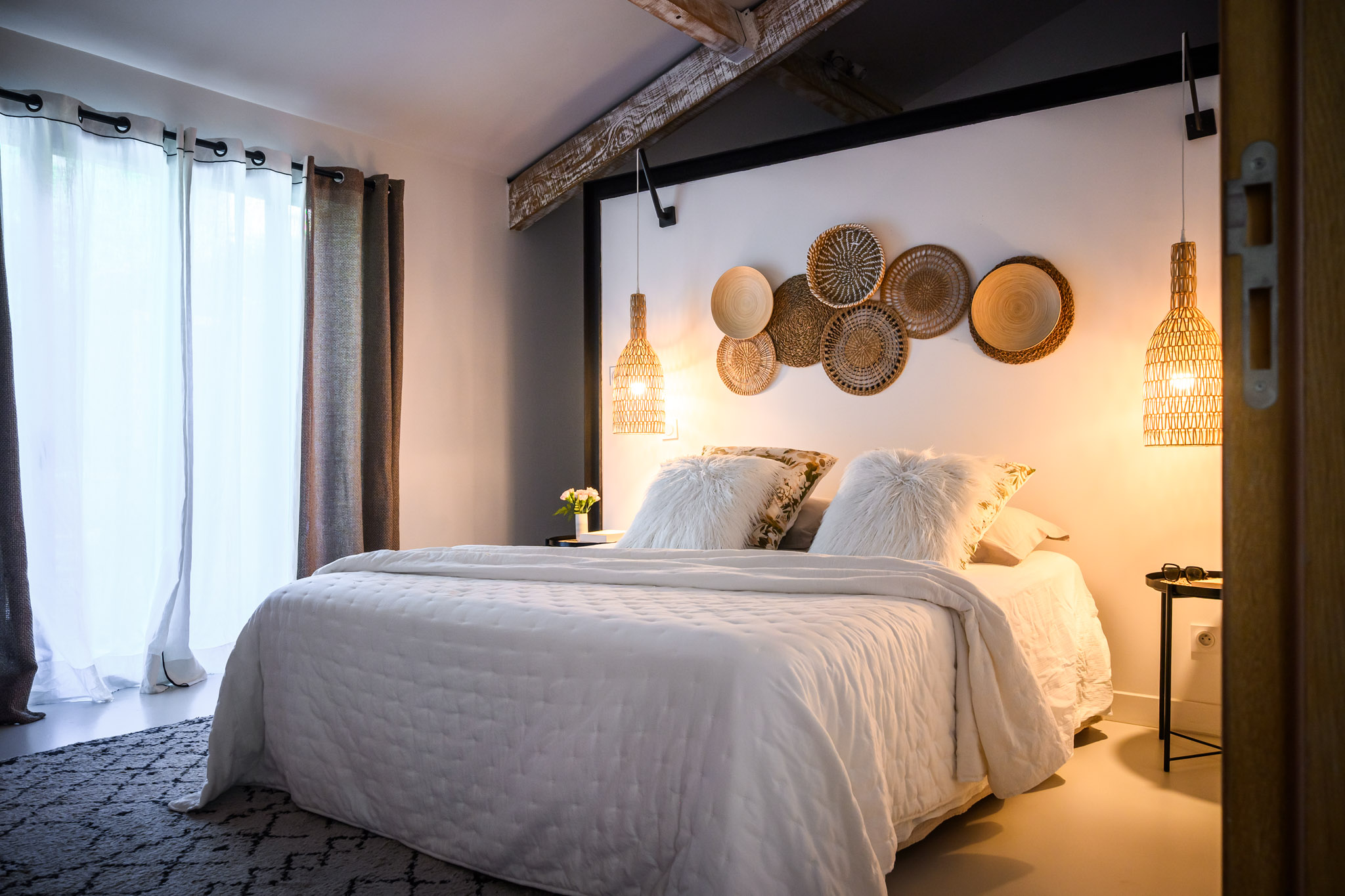 Chambre du loft de Carpentras avec lit double, décoration murale en rotin et suspensions lumineuses