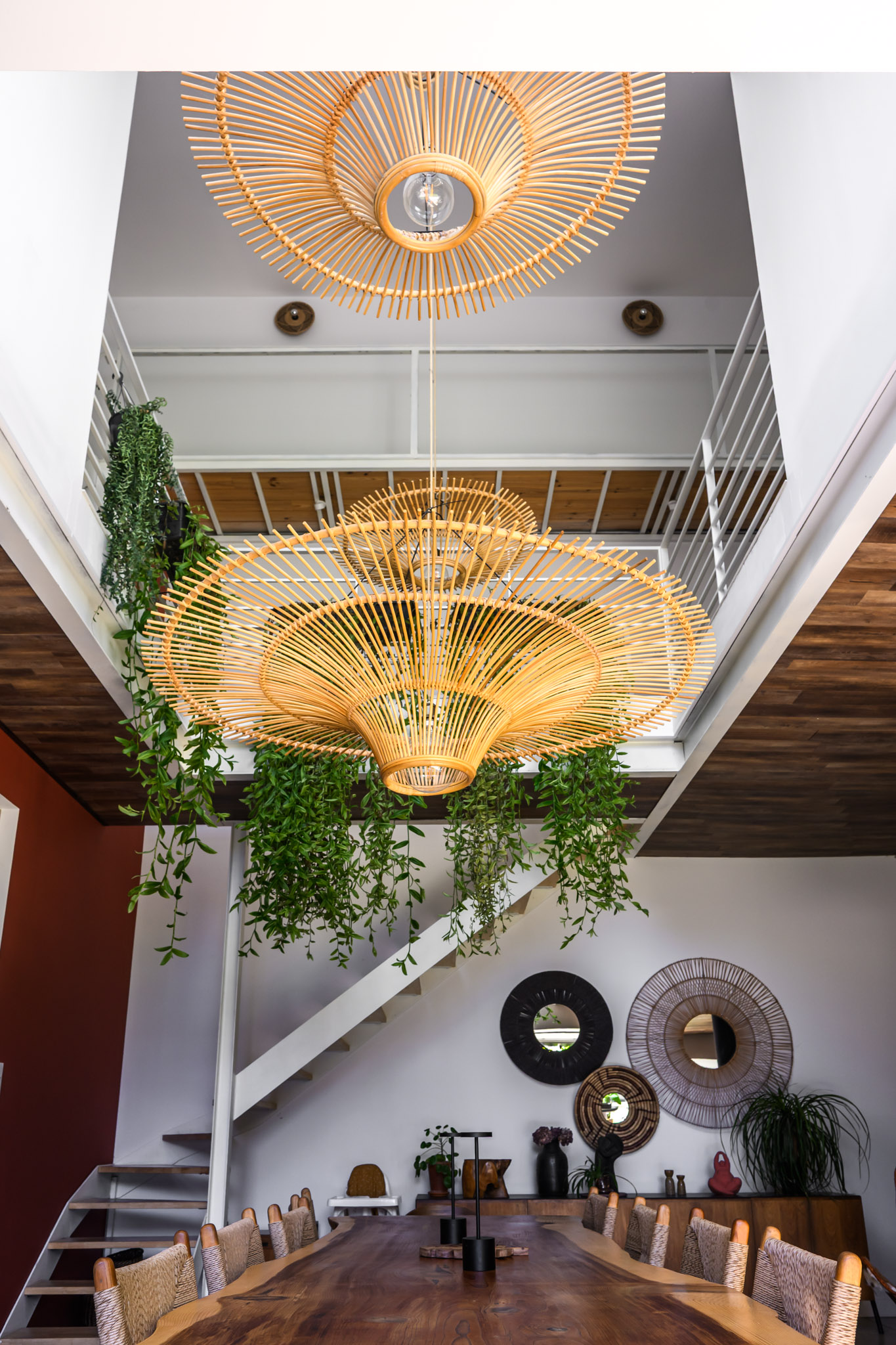 Vue intérieure du loft en location à Carpentras avec grande suspension en rotin, plantes suspendues et salon lumineux