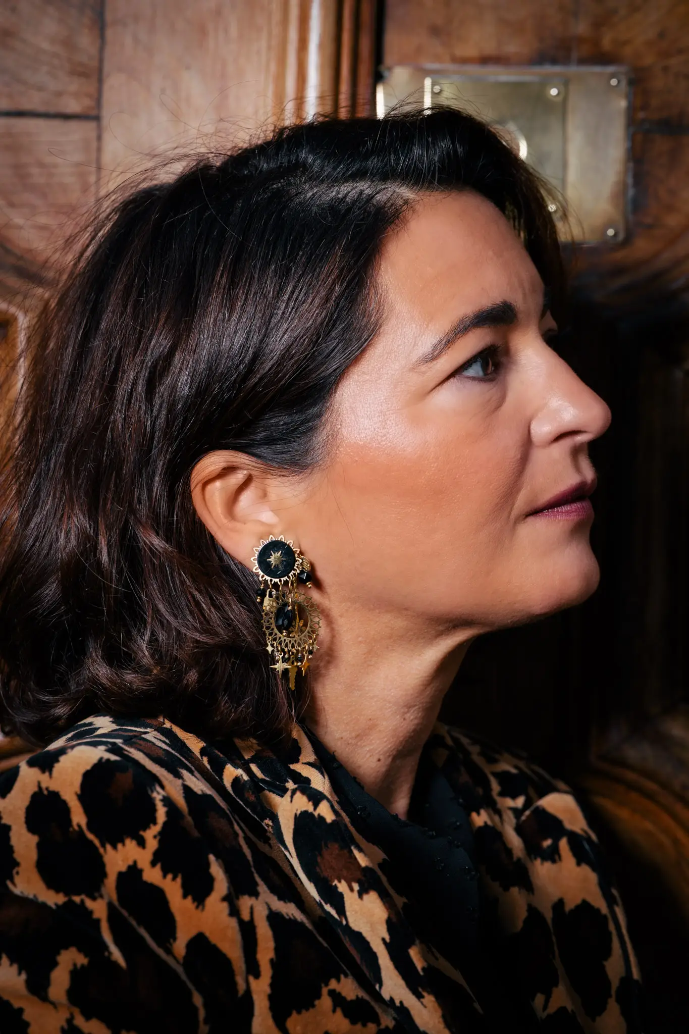 Détail fashion avec veste léopard et boucles d’oreilles dorées pour un lookbook mode haut de gamme.