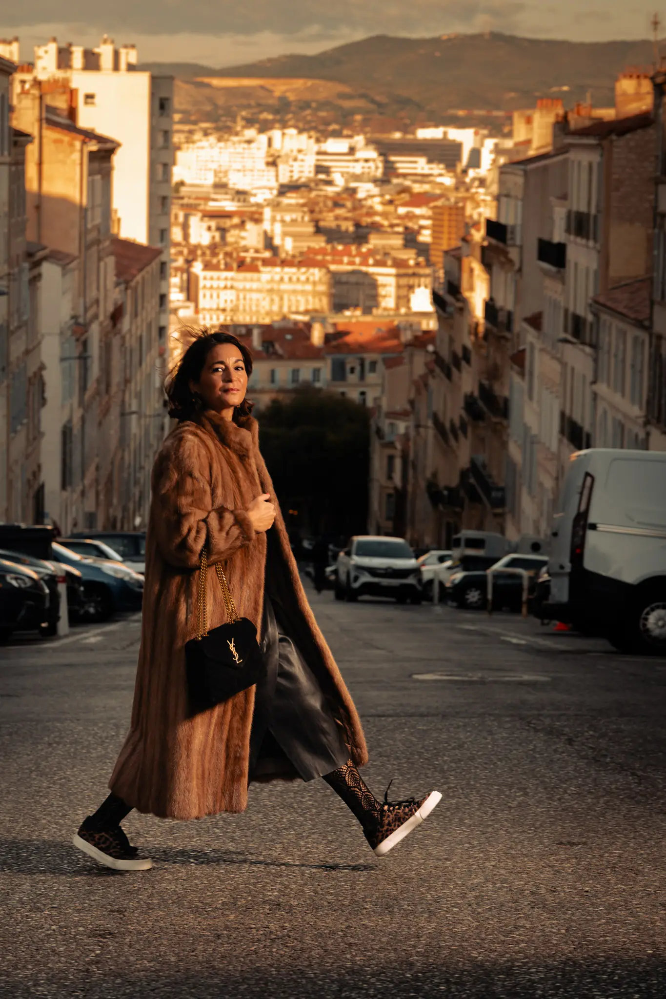 Silhouette chic en manteau de fourrure et sac YSL marchant dans une rue haussmannienne pour un lookbook fashion haut de gamme.