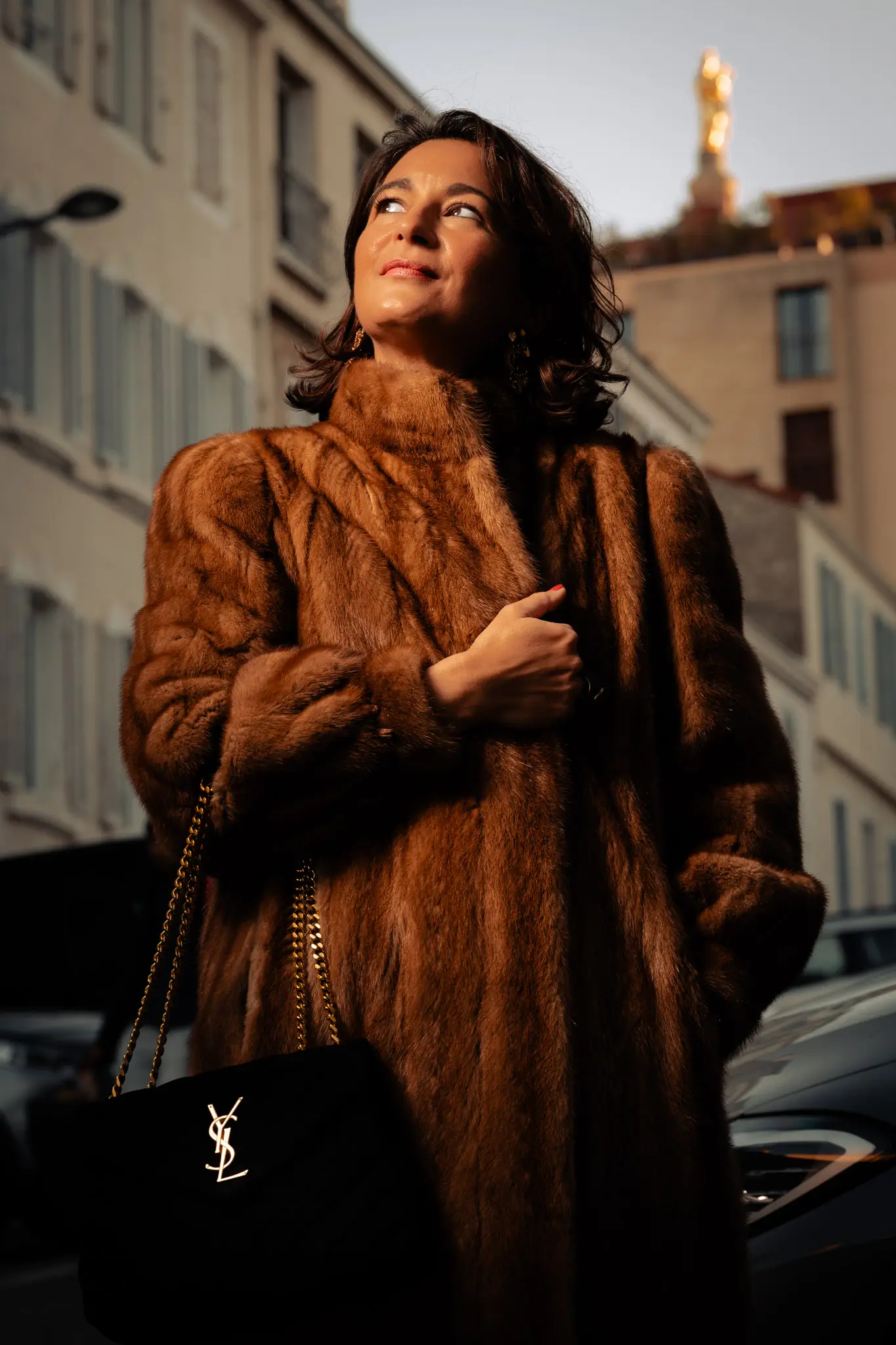 Silhouette chic en manteau de fourrure avec sac YSL et vue sur Notre Dame de la Garde pour un lookbook fashion haut de gamme.